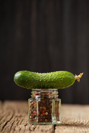 Hot pepper and fresh cucumber on a wooden background. A fresh cucumber lies on a jar of pepper close-up.の写真素材