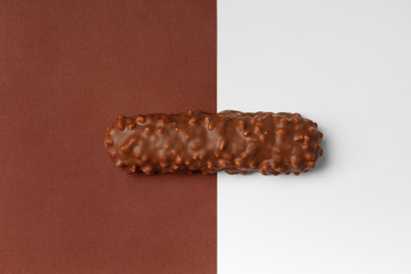 Milk chocolate on brown and white background, top view. Conceptual representation of two opposites in the theme of chocolate. Chocolate bar on a contrasting background.の写真素材