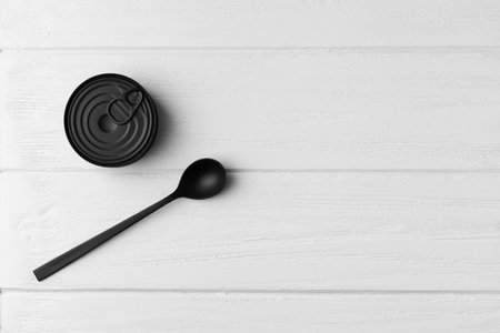 Black matte round closed tin can and black spoon on gray wooden background top view with space for text, tinned food, canned food, preserves.の写真素材