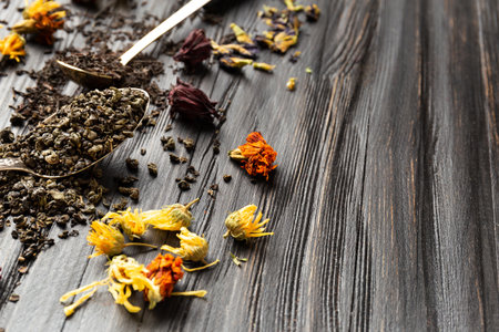 Composition of dry black and green tea in vintage spoons, dry flowers tea on a dark wooden background top view close-up. Different types of dry tea on a dark background.の写真素材