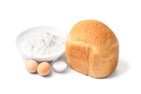 Fresh homemade bread with a crispy crust made in an automatic bread maker and baking ingredients isolated on a white background. Wheat flour, eggs, salt, freshly baked bread.の写真素材