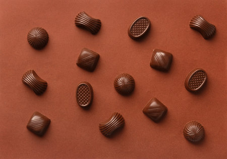 Mix of chocolate candies of various shapes on a brown background, assorted sweets, top view, flat layの写真素材