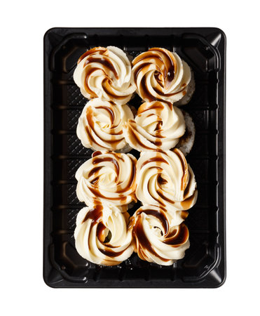 Sushi rolls with salmon, topped with cream cheese and sauce in a plastic package, chopsticks, ginger, sauce on a white background. Japanese, Asian cuisine, sushi delivery.の写真素材