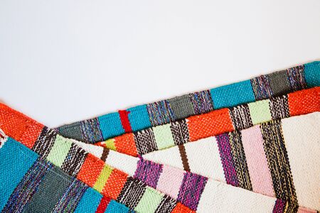 Several brightly colored striped textile mats on a white background. Colorful textile texture with space for text. Flat lay.の写真素材
