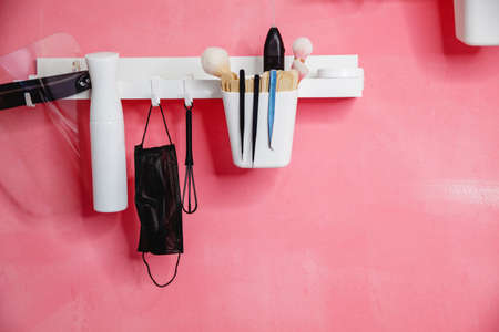 White shelves with bottles and tools on a pink wall in a beauty salonの写真素材