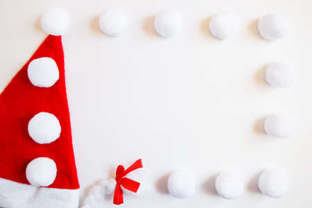 Frame of Santa Claus hat and white balls on a white background. Christmas flat layout with copyspaceの写真素材