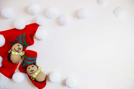 Santa hat, childish socks with animals and lots of white balls on a white background. Christmas flat lay with copyspaceの写真素材