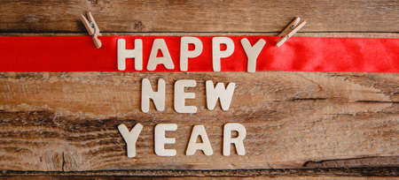 Happy new year inscription in wooden letters on a wooden background. The word happy on the red ribbon. Flat lay. High quality photoの写真素材