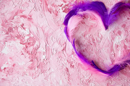 Purple heart-shaped feathers on a textured pink backgroundの写真素材