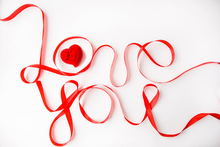 the inscription love you with a red ribbon on a white background and a red gift box in the shape of a heart for jewelryの写真素材