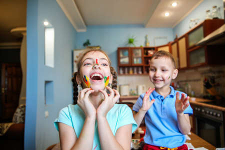 Smeared in paint children a boy and a girl fool around and laugh at home in the kitchenの写真素材