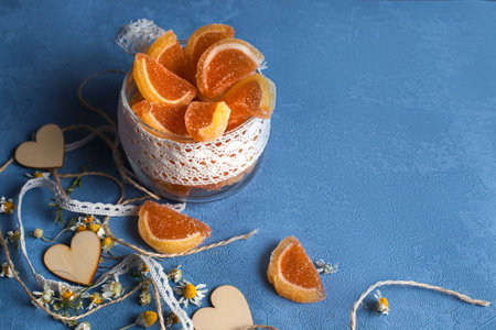 Dessert jar with marmalade on the blue background. There are ribbons and wooden hearts near it.の素材