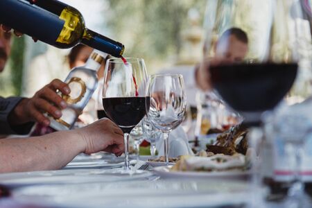 The process of pouring red wine into a glass. Public open air feastの写真素材