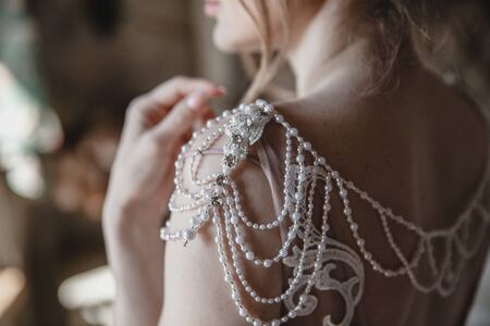 Decorative elements of the wedding dress on the brides shoulders. Threads with pearl beadsの写真素材