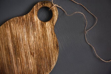 A round, worn wooden chopping Board with twine on a gray background is a scratched chopping Board. Close upの写真素材