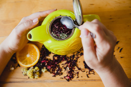 The process of making herbal tea in a green teapot on a wooden table. The view from the top