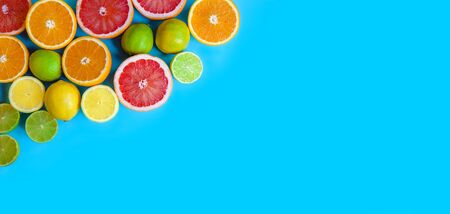 Blue background with different sliced citrus - oranges, grapefruits, lemons and limes. Flat layout with space for text. Bannerの写真素材