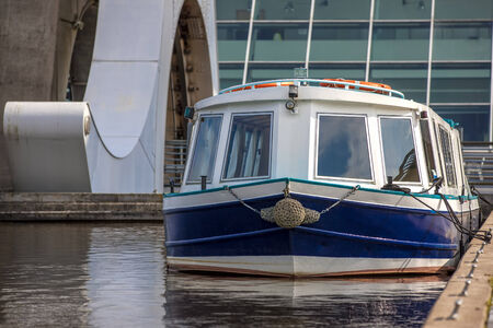 White and Blue boat moored near Falkirk Wheel, Scotland. The Falkirk Wheel is a rotating boat lift in Falkirk, Scotland, connecting the Forth and Clyde Canal with the Union Canal.の写真素材