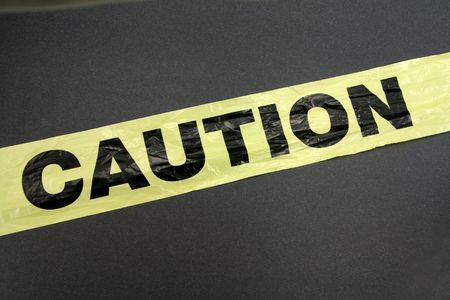 yellow plastic caution tape with dark backgroundの写真素材