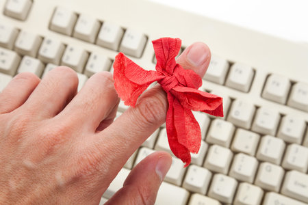 Red bow on finger and computer keyboard