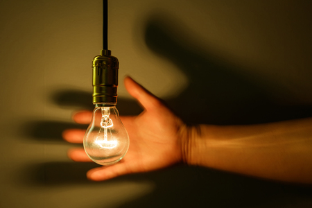 light bulb and hand with dark backgroundの写真素材