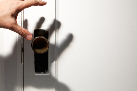 old wooden door with door knob, hand shadow.の写真素材
