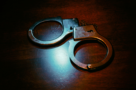 Metal handcuffs with dark background, close up.の写真素材