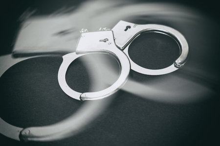 Metal handcuffs with dark background, close up.の写真素材