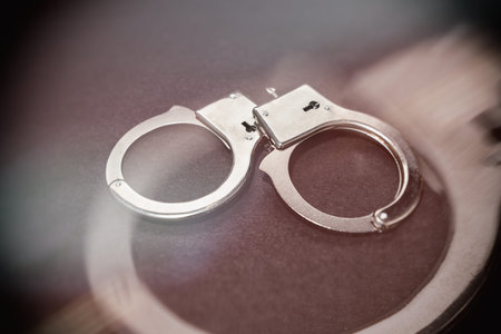 Metal handcuffs with dark background, close up.