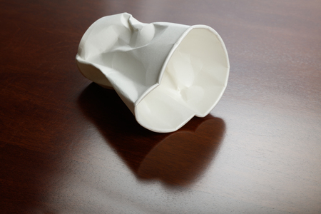 Crumbled White paper coffee cup on table.の写真素材