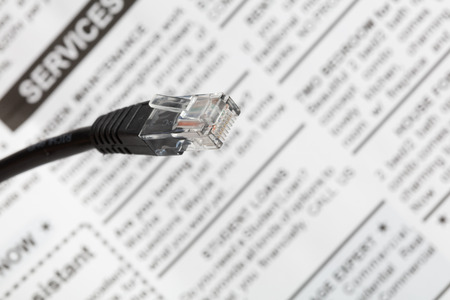 Black network cable plug with newspaper , close up view.の写真素材