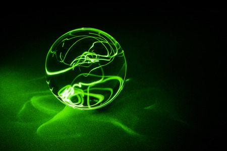 Transparent Crystal ball on black with green light, close up.の写真素材