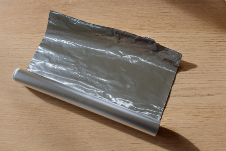 Aluminum foil roll on wood table, close up.の写真素材
