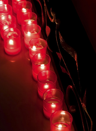 Rows of burning candles inside a church in the darkの写真素材