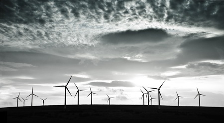 Silhouettes of wind turbines against dramatic cloudsの写真素材