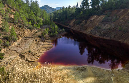 Acidic red lake in abandoned open pit mine in a forest, result of the pyrite ore extraction in the areaの写真素材