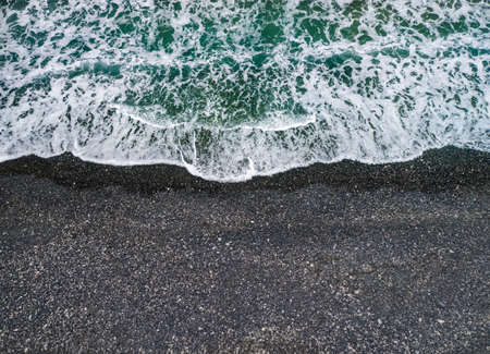Stormy weather, sea waves breaking on a shore with volcanic black sand, background with copy spaceの写真素材