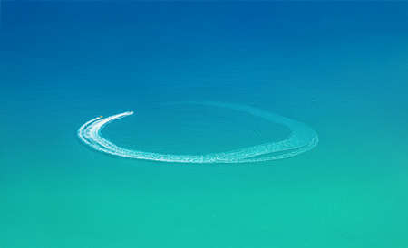Water sports at the beach aerial view. Speedboat and wave slider leave circular trail on waterの写真素材