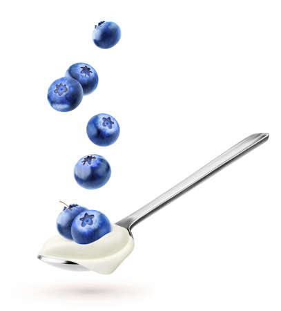 Isolated yogurt with fruits. Spoon with natural yogurt and falling blueberries isolated on white backgroundの写真素材