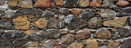 Old rough wall of multicolored natural stone. Abandoned building texture