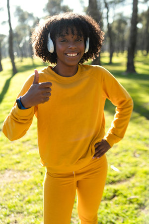 A girl dressed in yellow tracksuit stretching before starting a run in the park.