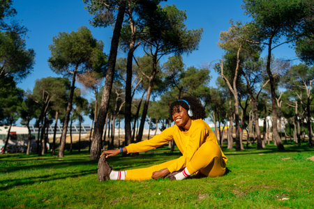 A girl dressed in yellow tracksuit stretching before starting a run in the park.の写真素材