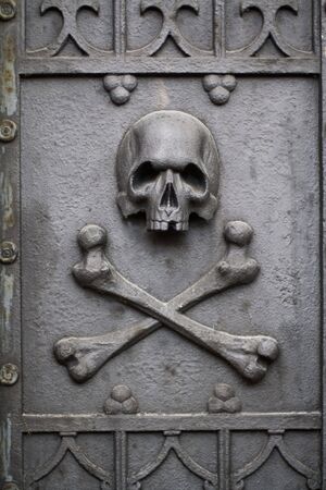 Old metal skull with bones on grave door.の写真素材