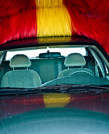 car in wash, colorful brush. Front window, no driver, visible Steering Wheel and seat.の写真素材