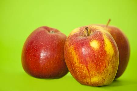 three red juicy apples on green backgroundの写真素材