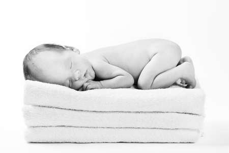 little baby sleeping on the stacked towelsの写真素材