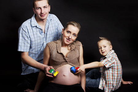 pregnant woman with son and husband on black background