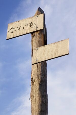 a wooden signpost on a sky background showing a bike routeの写真素材