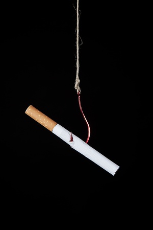 a cigarette hanging on a hook as a symbole of nicotine addictionの写真素材