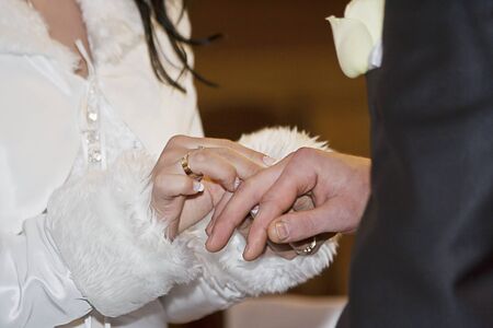 bride putting on a wedding ring for her husbandの写真素材